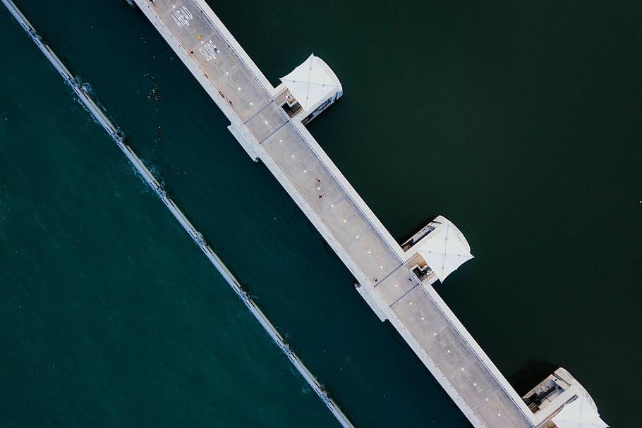 aerial photo of white concrete structure near body of water, gray asphalt bridge with body of water HD wallpaper
