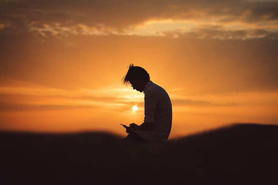 silhouette of man using smartphone during sunset, man wearing shirt against light at golden hour HD wallpaper