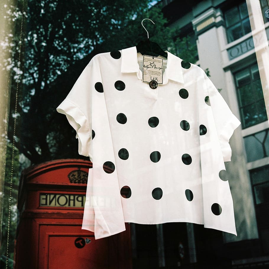 white and black polka-dot poncho top, white and black polka-dot short-sleeved collared blouse hanging behind glass panel window HD wallpaper
