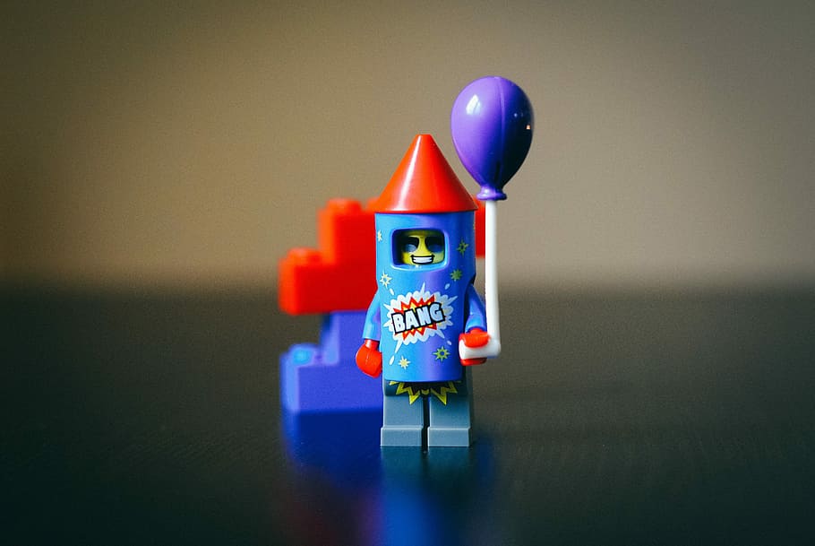 teal, red, and purple LEGO plastic firecracker toy in focus photography, macro photography of blue and red Lego toy on top of table HD wallpaper