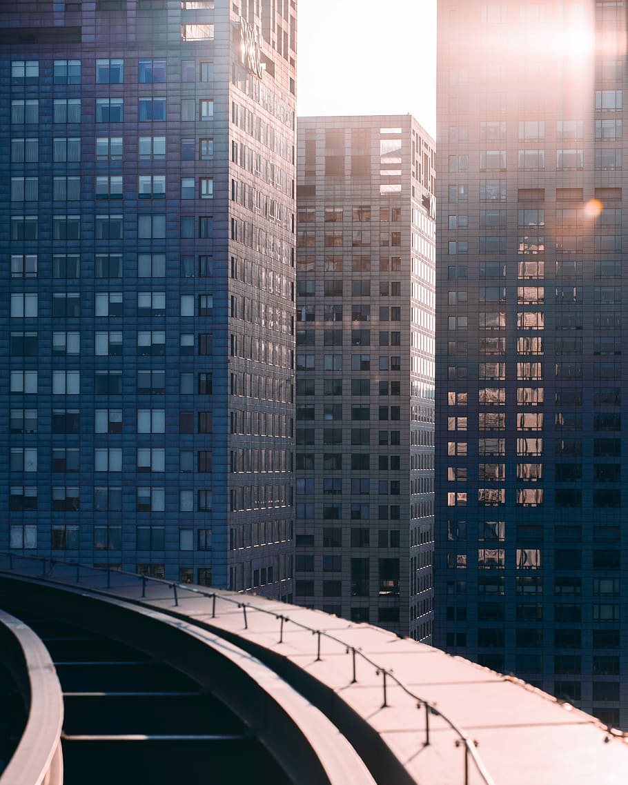 gray concrete building in front way, three curtain wall buildings near concrete pathway at daytime HD wallpaper