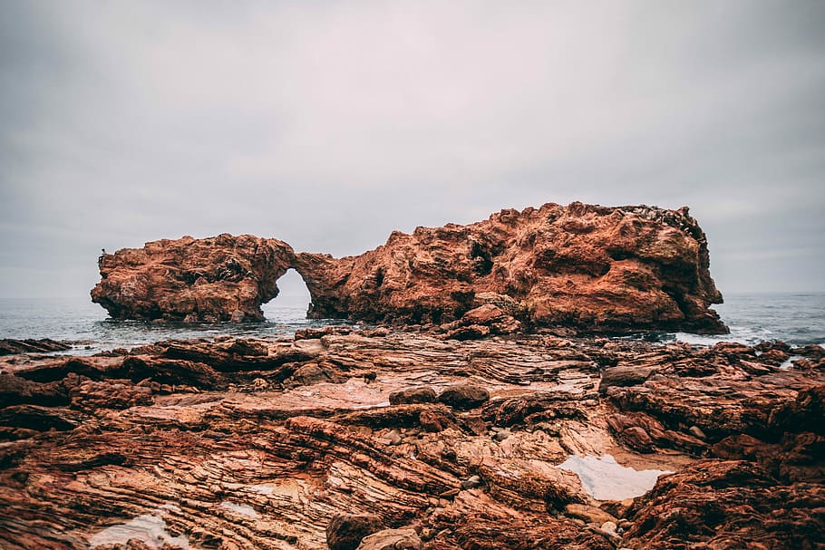 rock formation on body of water, two brown rock monoliths near shore HD wallpaper
