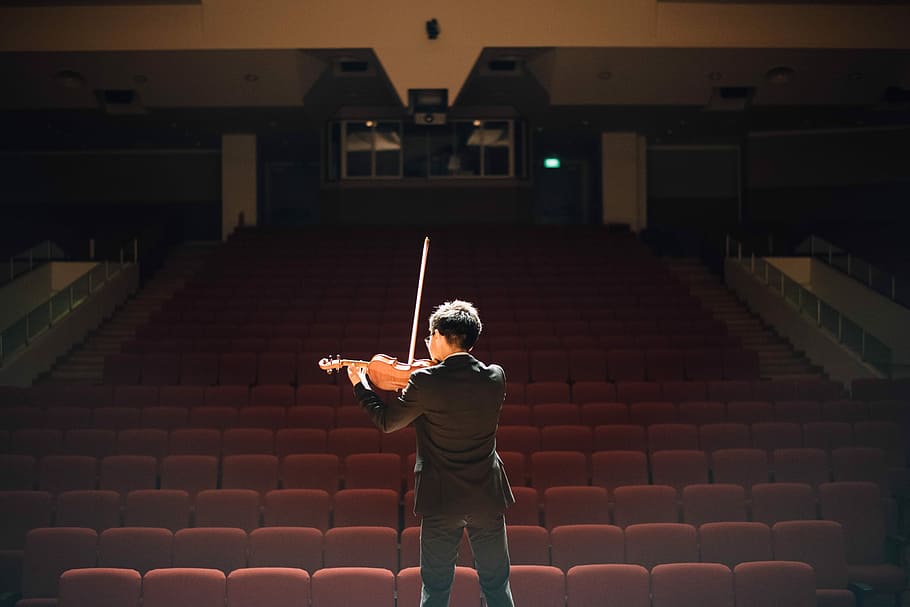 man standing in front of stage playing violin, man wearing black long-sleeved shirt playing violin in front of chairs, HD wallpaper