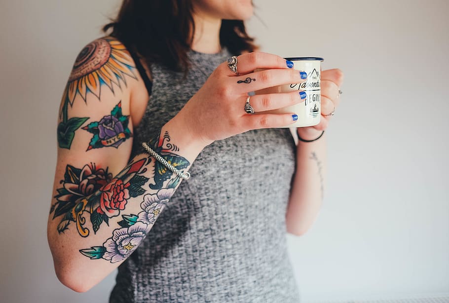 woman standing while holding white mug, tattoos, tattooing, arm