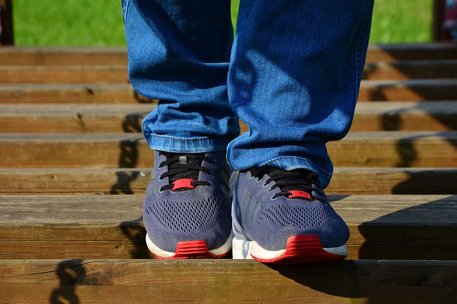 person wearing blue denim jeans walking on brown concrete stair HD wallpaper