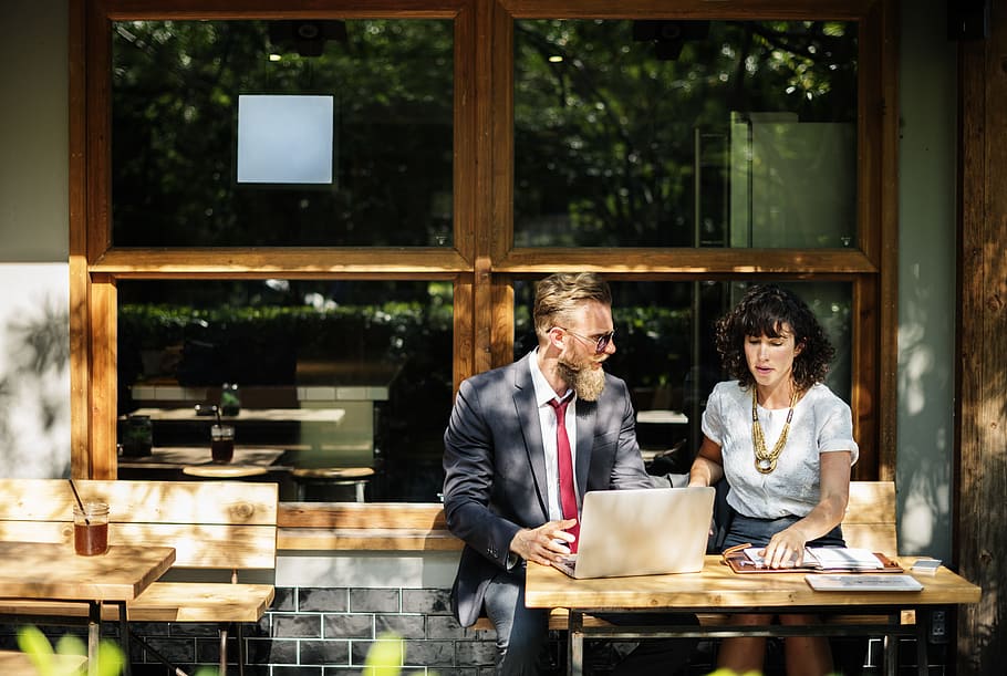 man and woman siting in front of brown wooden table during daytime HD wallpaper
