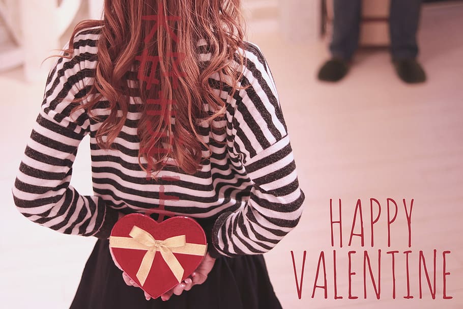 woman in white and black stripe sweater and black skirt hiding a heart-shaped gift box on her back while walking toward a person in black shoes HD wallpaper