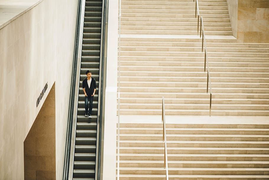 man standing on escalator near beige stairs taken during daytime, HD wallpaper