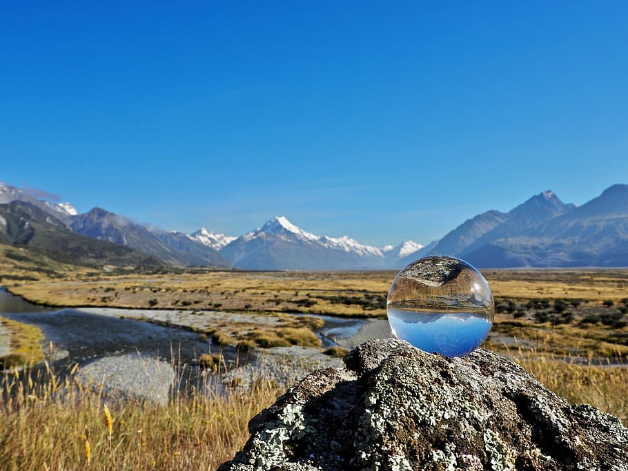 landscape view of mountains, clear glass paperweight on brown rock under blue sky during daytime HD wallpaper