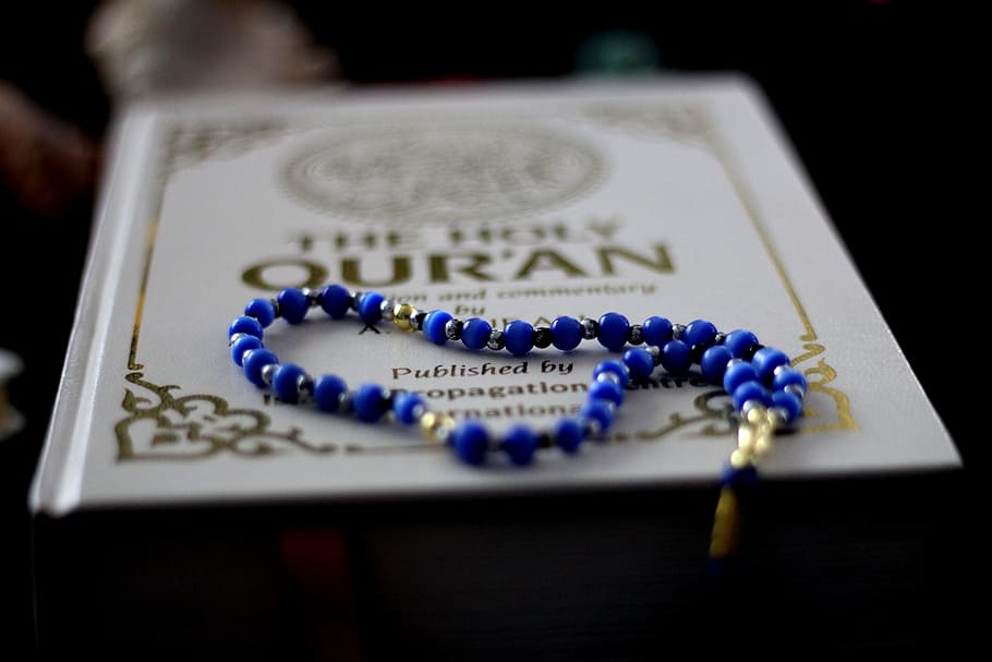 selective focus photography of beaded blue necklace on book, quran