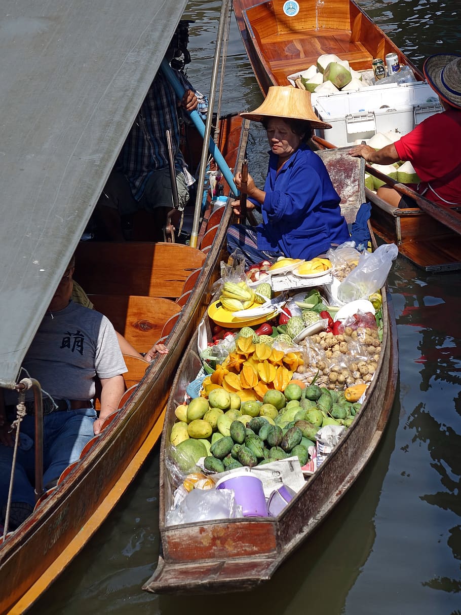woman riding on boat full of fruits, damnoen saduak floating market
