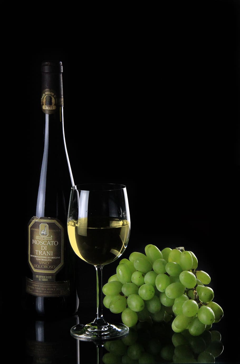 Moscato Di Trani wine bottle , wine glass and green grapes, still life