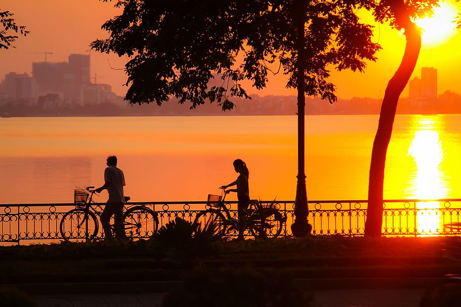 man and woman holding their bikes while walking, sunset, west lake, HD wallpaper