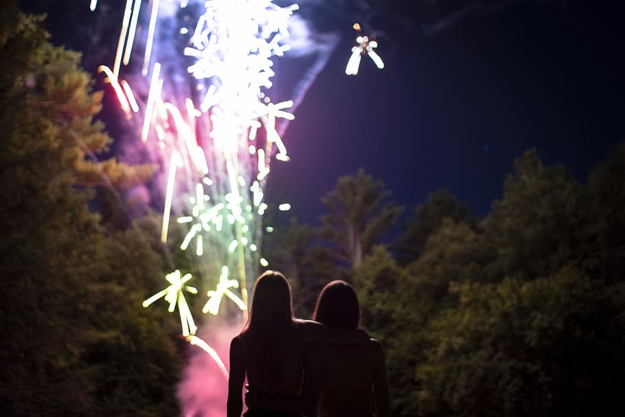 two people standing near firework show, two women watching fireworks at nighttime HD wallpaper