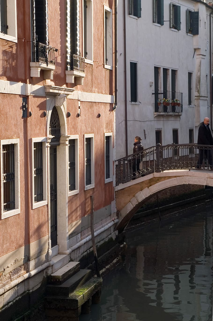 woman walking in bridge beside brown concrete building, Venice river and house HD wallpaper