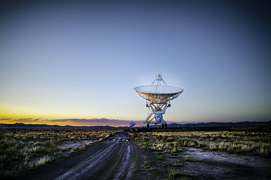 white radar telescope on grass field, road towards white satellite