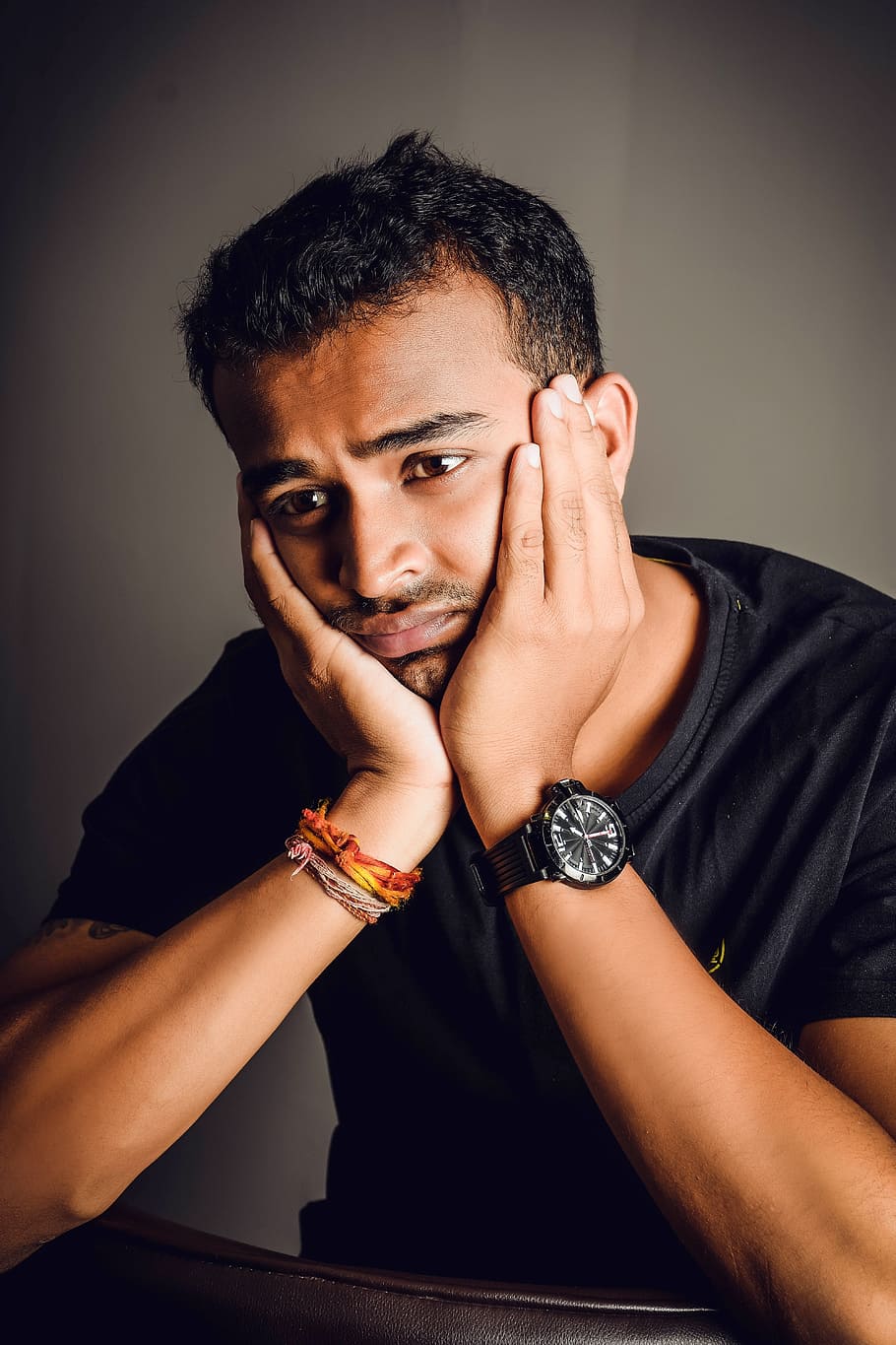 man wearing black crew-neck shirt sitting with hands on face HD wallpaper
