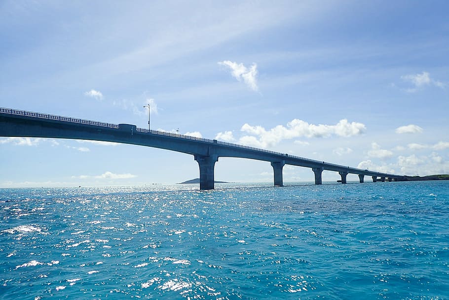 gray concrete bridge on body of water under cloudy clear sky HD wallpaper