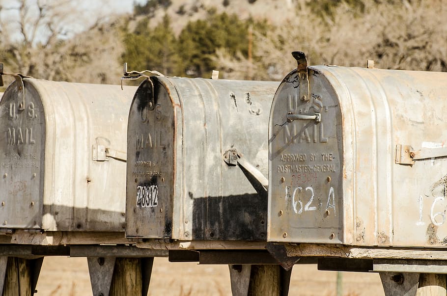 closeup photography of three gray U.S. mailboxes, rural mail
