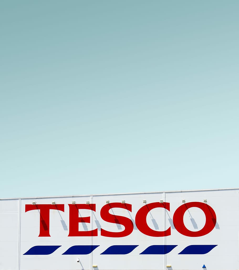 Tesco building under clear blue sky, Tesco logo, supermarket