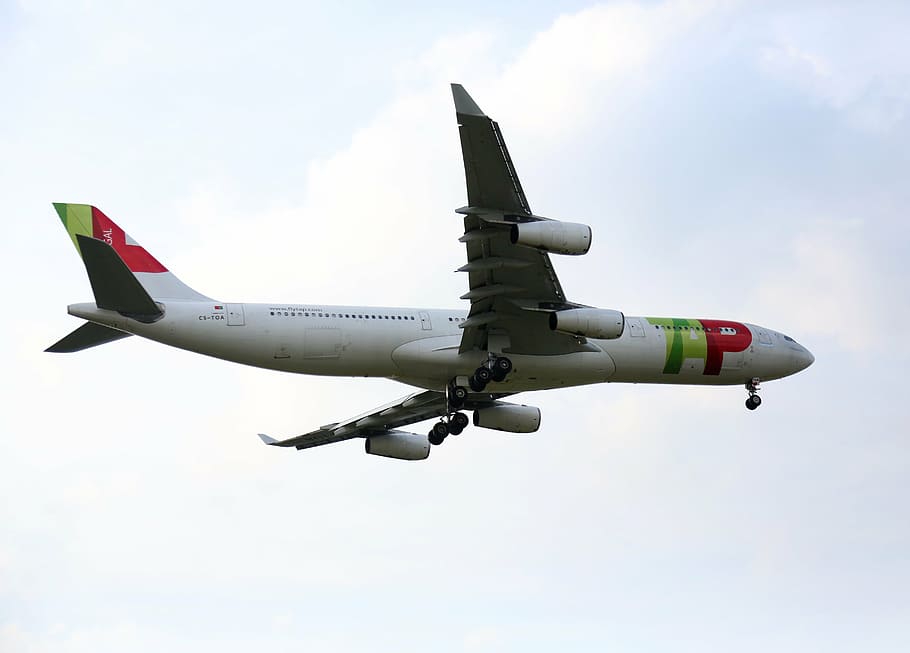 low-angle photography of white, green, and red passenger plane with opened landing gear while inflight