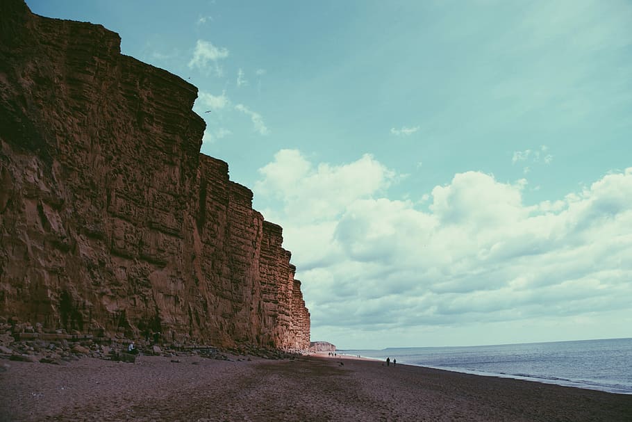 brown mountain near sea during daytime, beach with mountain on side HD wallpaper
