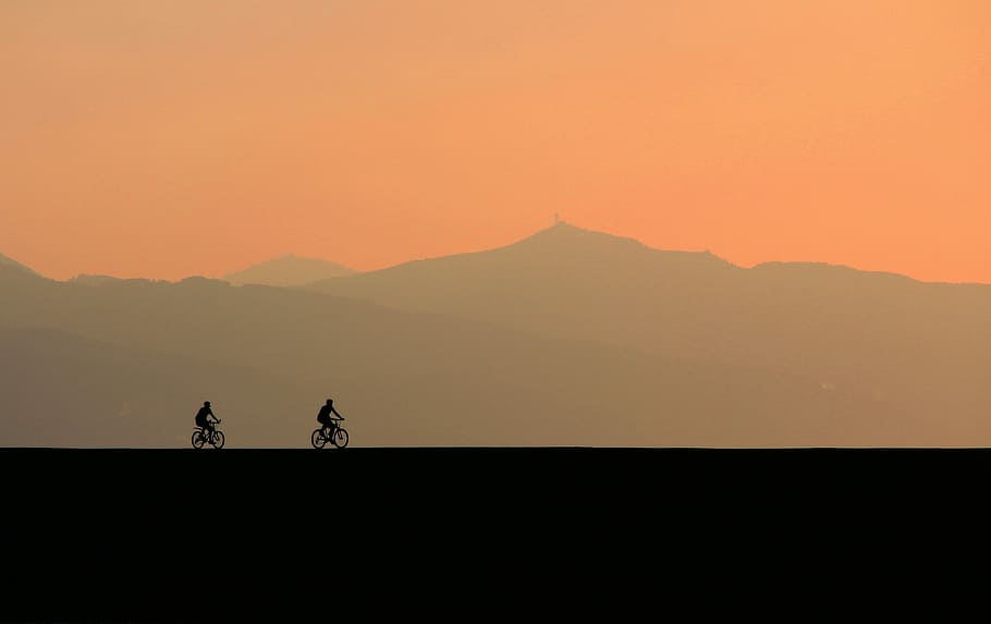 two person riding on bicycle on black surface during golden hour HD wallpaper