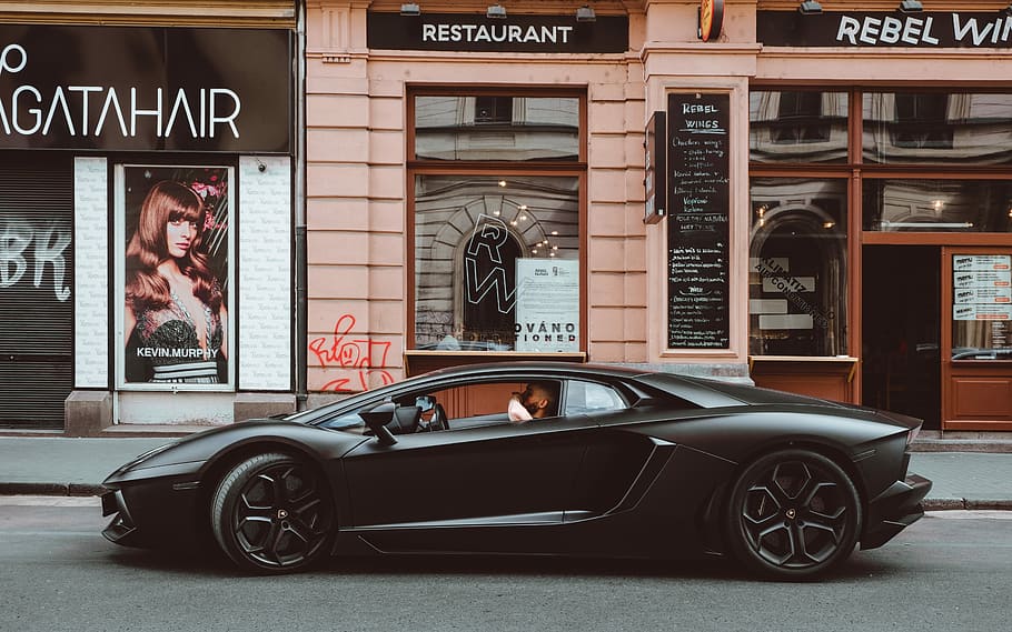 black Lamborghini on the street, photo of person in black sports car beside restaurant