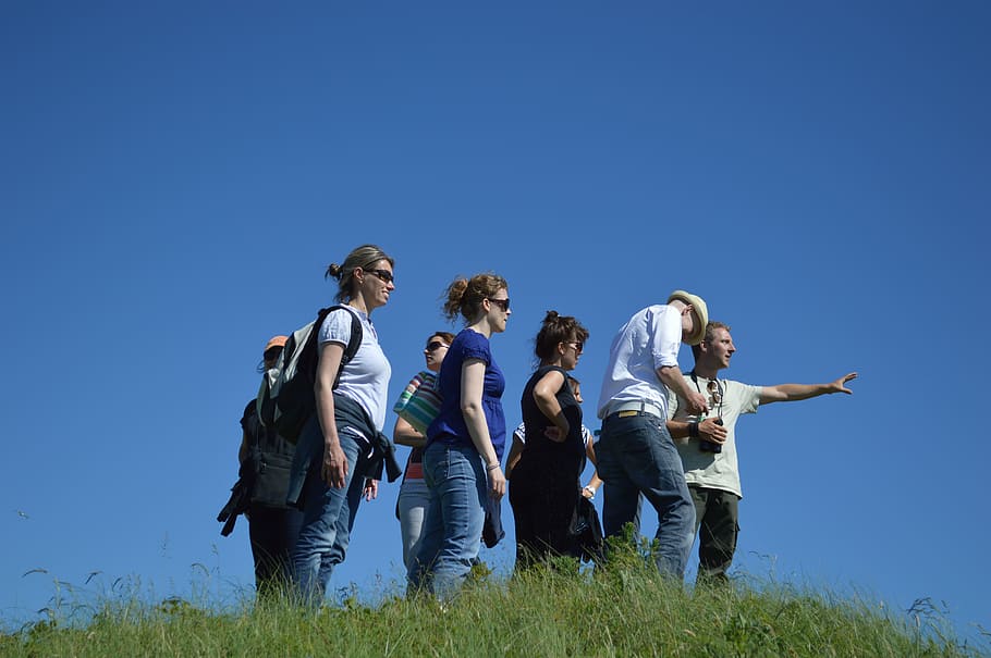 group of people standing on green grass field under blue sky HD wallpaper
