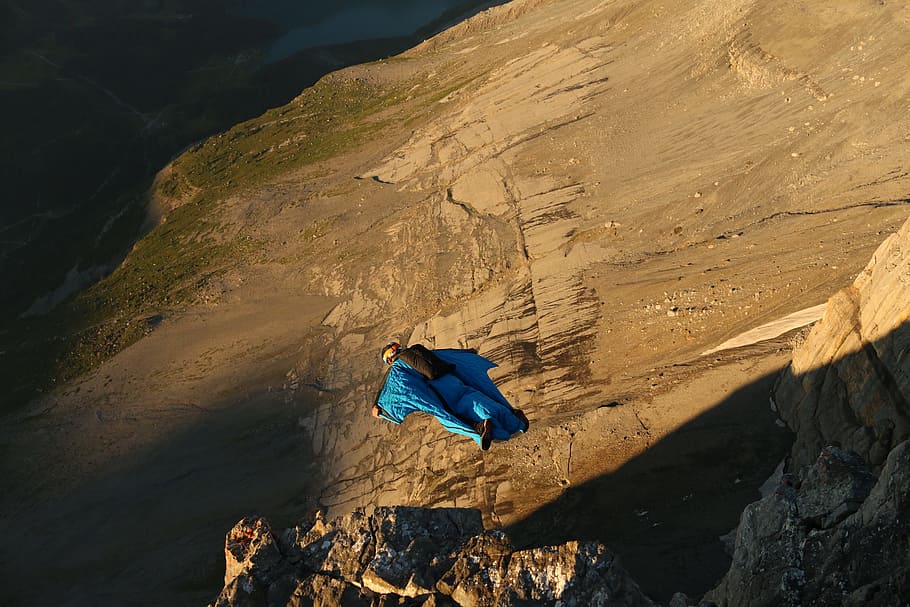 down down, person on cliff at daytime, mountain, wingsuit, jump