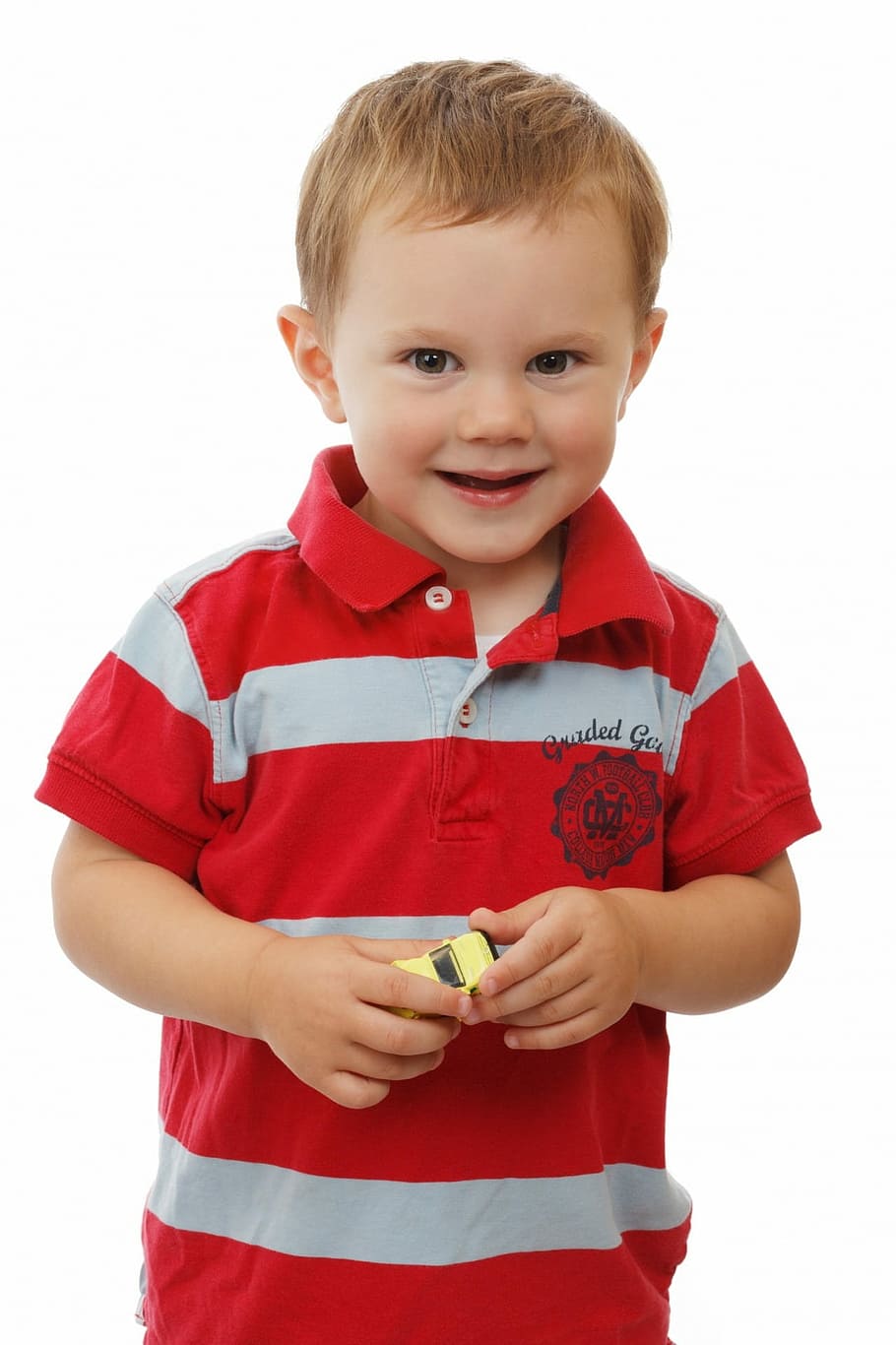 boy in red and white striped polo shirt holding yellow toy car