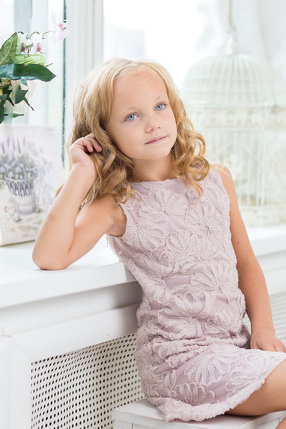 girl wearing purple floral boat-neck sleeveless dress sitting on white wooden bench