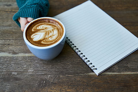 white ceramic cup beside white spring notebook on brown surface HD wallpaper