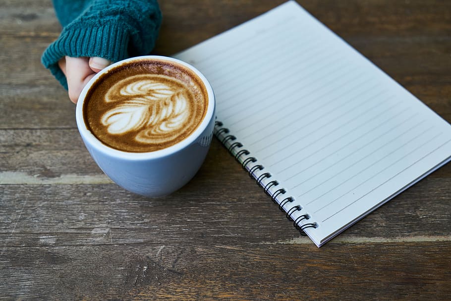 white ceramic cup beside white spring notebook on brown surface HD wallpaper