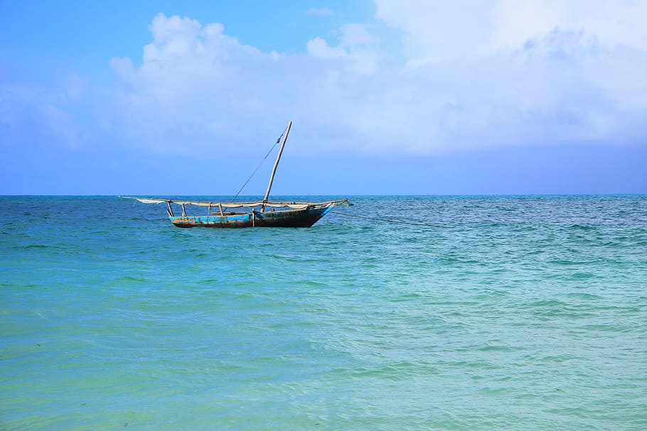 brown and blue wooden boat on body of water during daytime, dhow