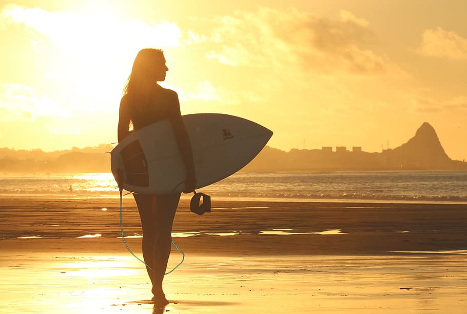 silhouette photography of woman holding surfboard, beach, clouds