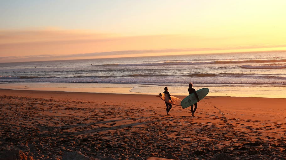 two surfers walking on sand going on water, two people carrying surfboard near shoreline, HD wallpaper