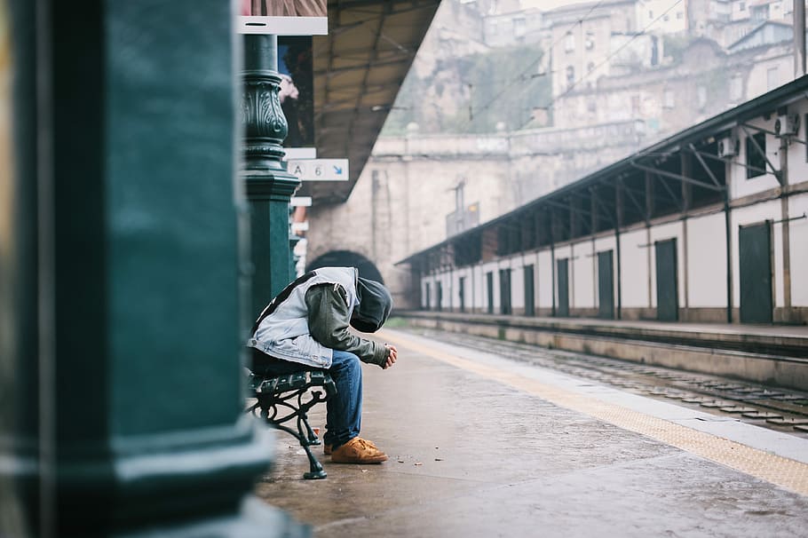 man sitting on bench, person sitting on black bench in train station HD wallpaper