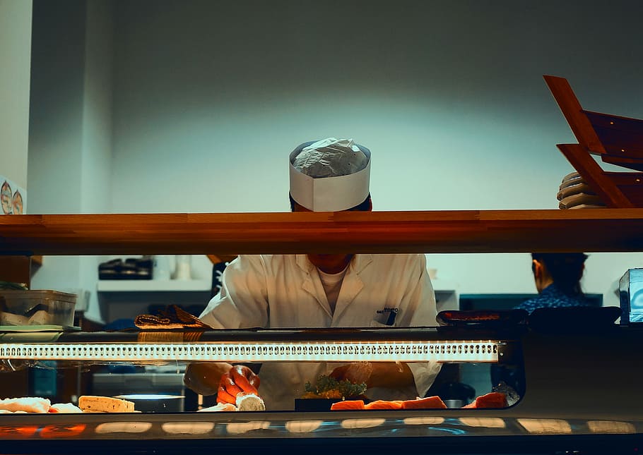 man preparing sushi dish, Eastern-style chef fronting display counter HD wallpaper