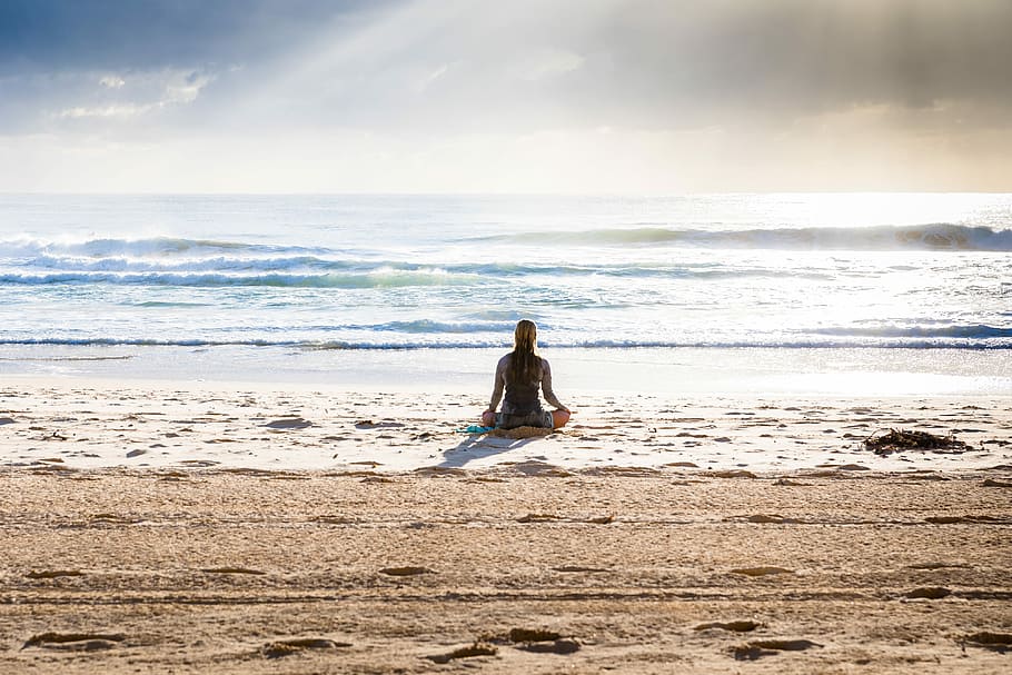 woman sitting on seashore, woman sitting on seashore under white sky and blue clouds at daytime HD wallpaper