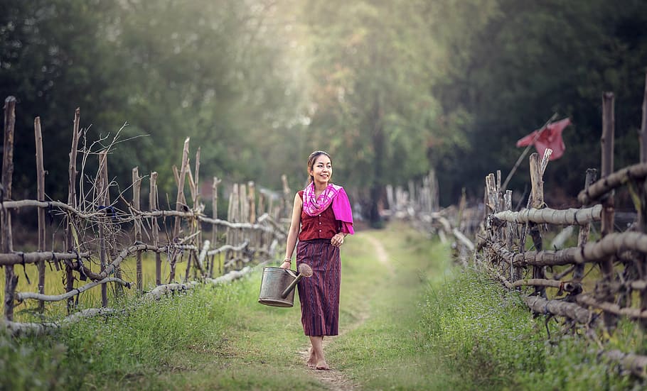 woman wearing red and purple dress, watering, for farming, smiling