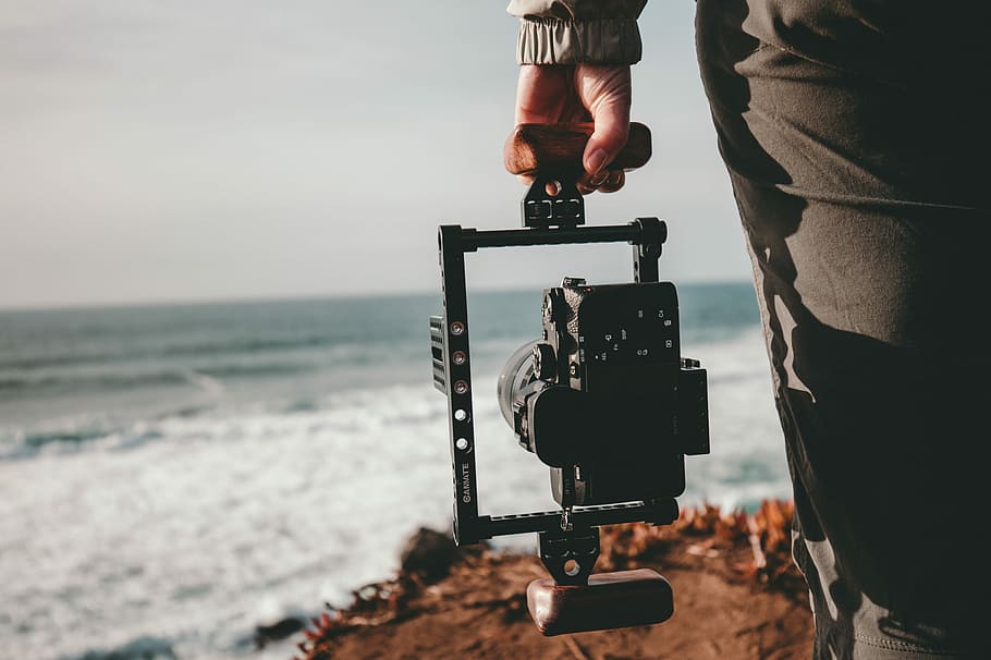 person holding camera, selective focus photography of person holding camera with gimbal facing sea HD wallpaper