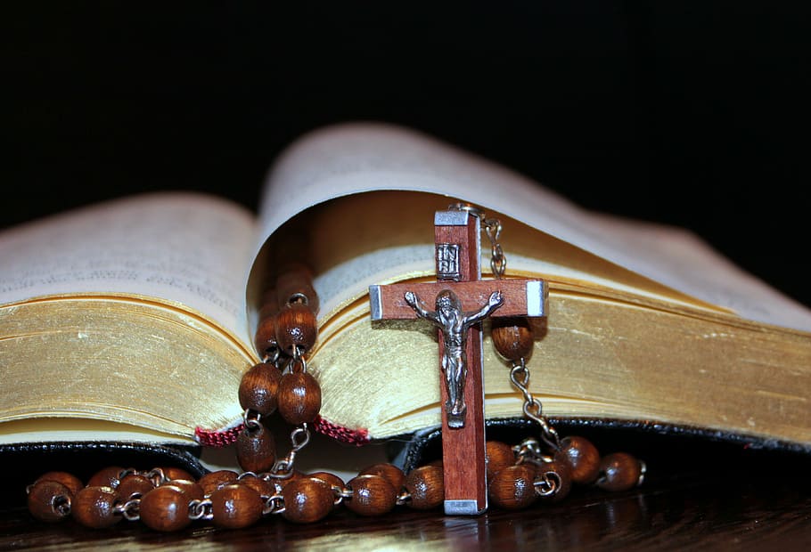 brown rosary and open bible, cross, prayer book, gold edge, pages