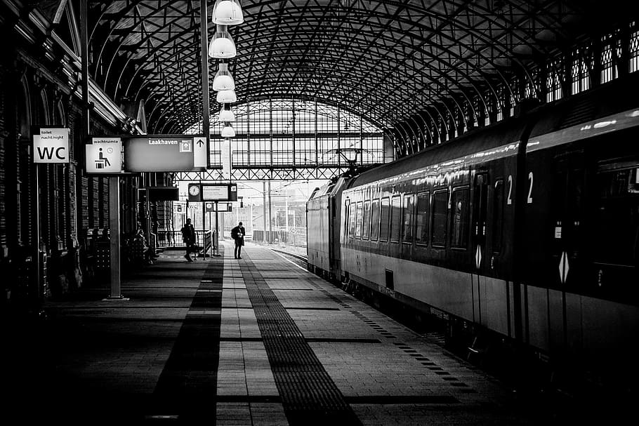 black and white photo of train on station, grayscale photography of two person standing on train station HD wallpaper