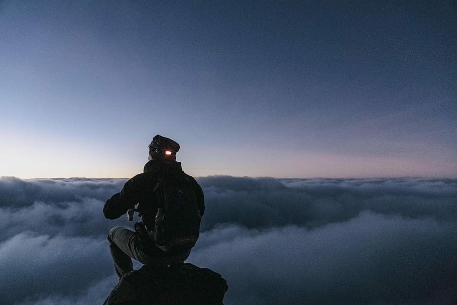 man sitting on top of the mountain, man sitting on rock while looking at sea of clouds HD wallpaper