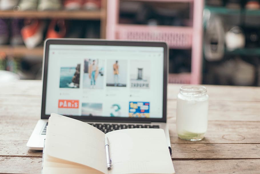turned on MacBook Pro beside glass jar and brown journal, black laptop computer HD wallpaper