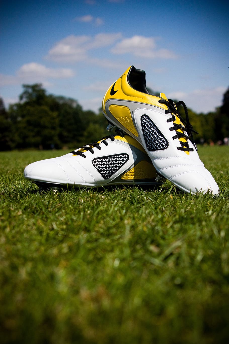 pair of white-and-yellow Nike soccer cleats on field during daytime, HD wallpaper