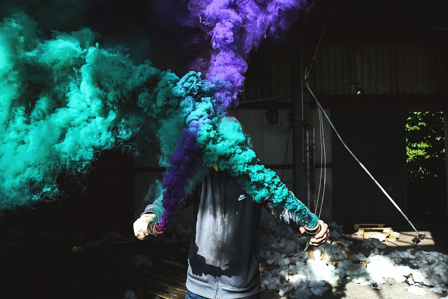 person holding purple and green smoker bottle during daytime, purple and green smokes