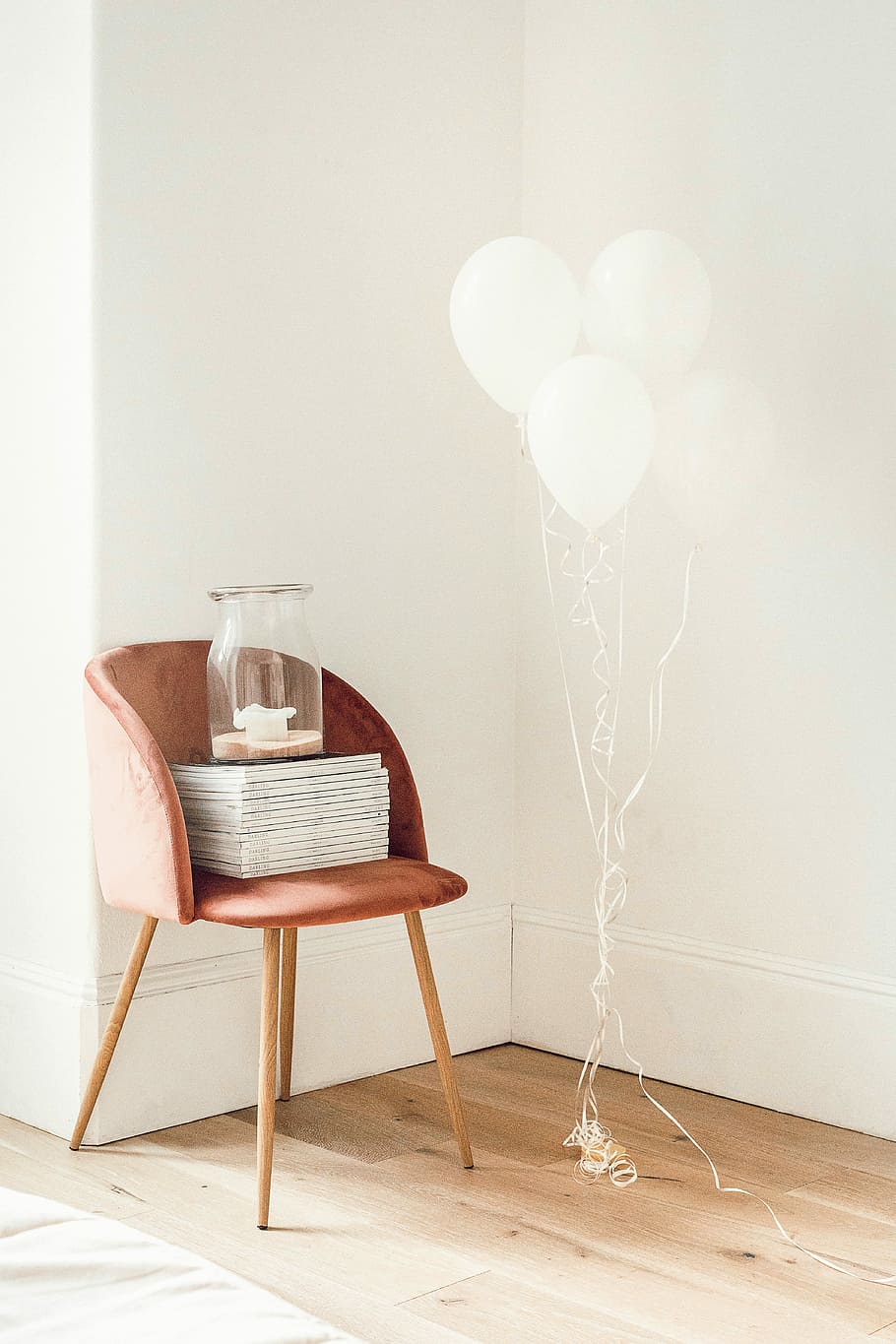 white balloons beside jar on book and chair, clear glass jar on top of chair beside balloons