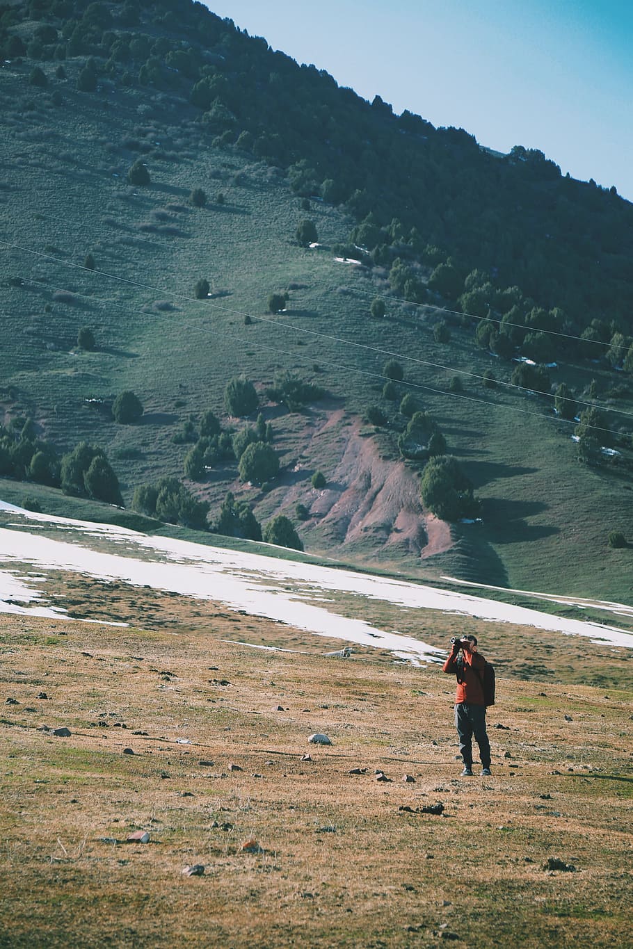 man wearing orange shirt hiking, man taking a photo of mountian HD wallpaper